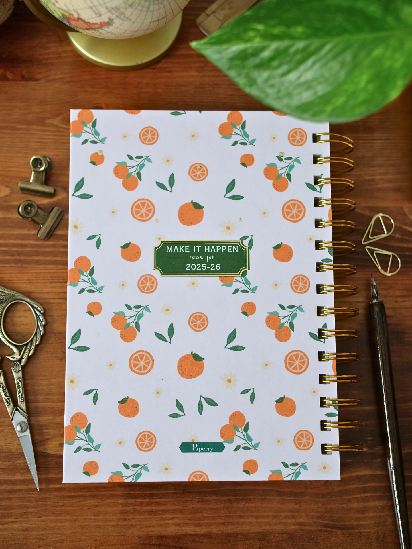 Notebook with orange pattern on a wooden surface with stationery items